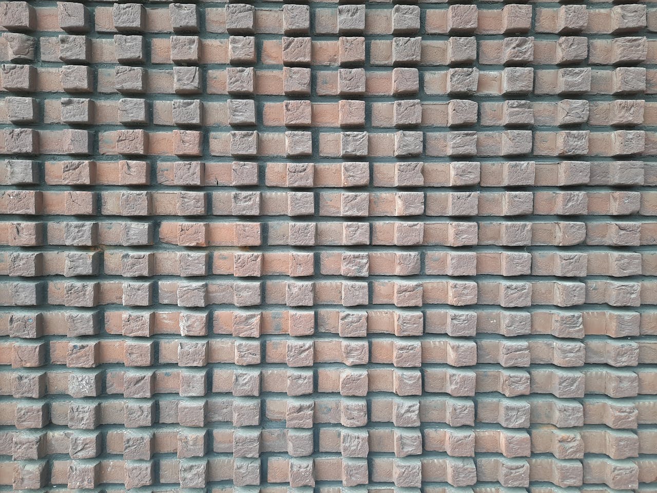 who-we-are Close-up texture of a structured brick wall creating a geometric pattern.