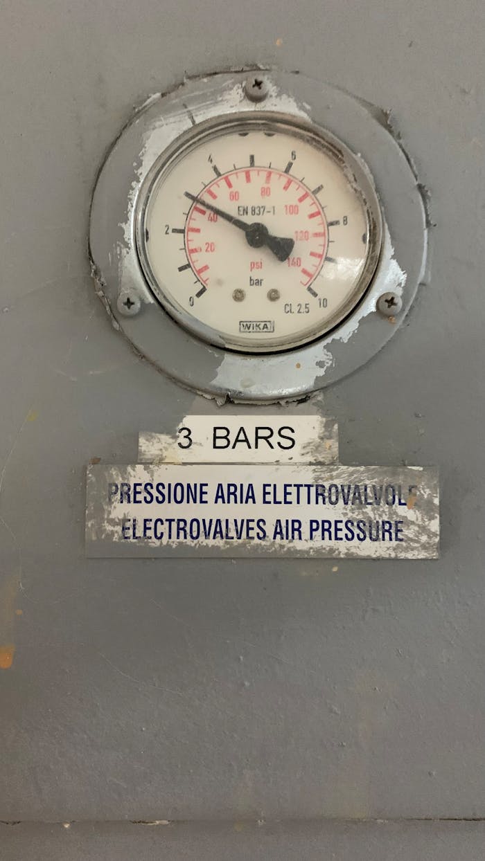 Close-up of a pressure gauge showing 3 bars in an industrial setting.
