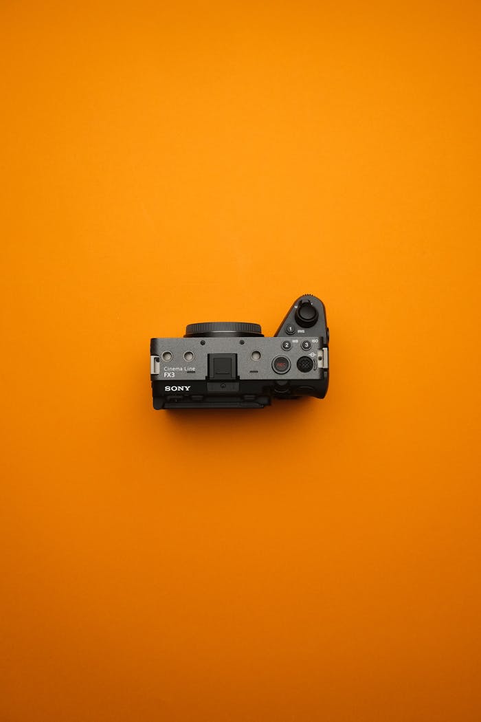 Sleek mirrorless camera on an orange background, perfect for creative studio setups and filmmaking concepts.